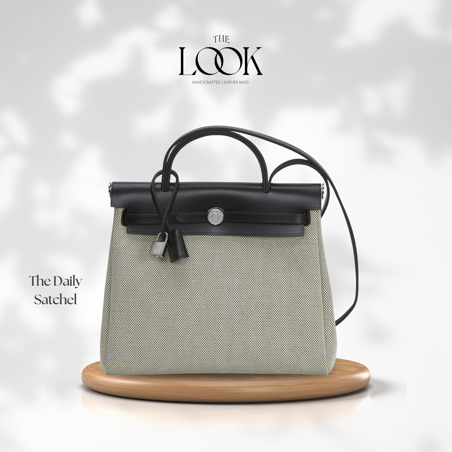 Black and gray satchel bag on a wooden stand with 'The Look' branding. | The Look Officiel
