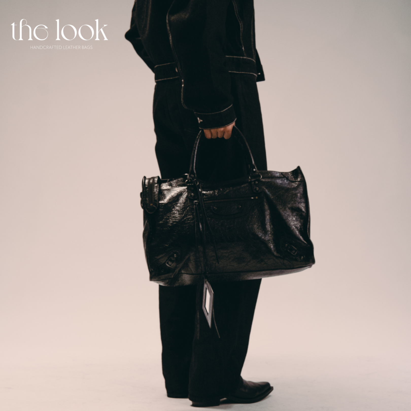 Model holding Biker Satchel Jumbo black goatskin braided handles front view gunmetal hardware