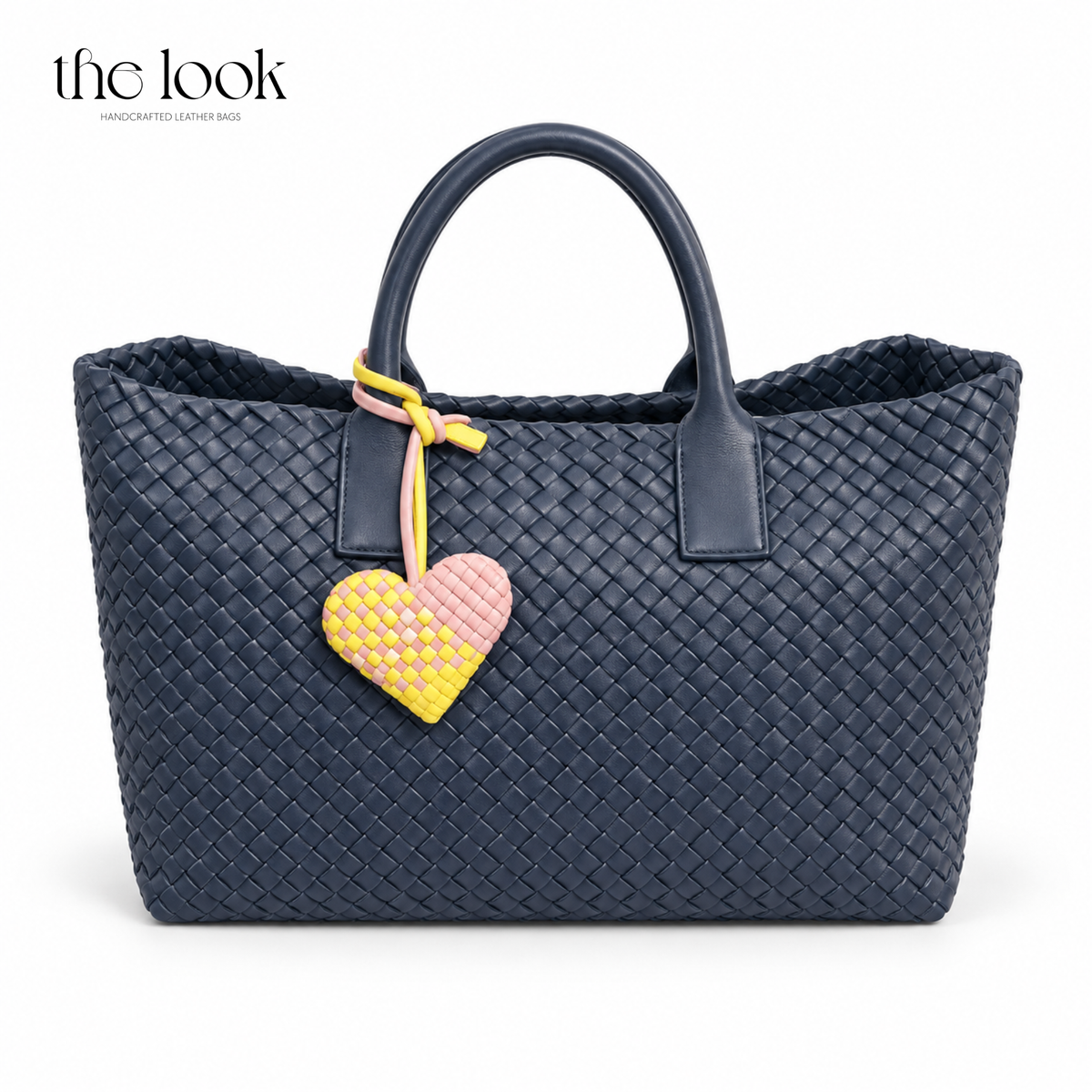 The Loop Amour woven leather heart bag charm in Pink Lemonade on a navy woven tote