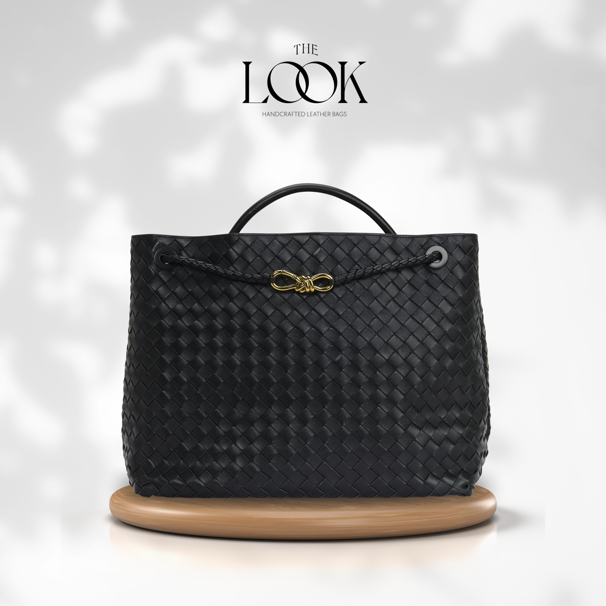 The Loop Jumbo Satchel in Black full-grain woven lambskin leather with top handle and gold hardware.