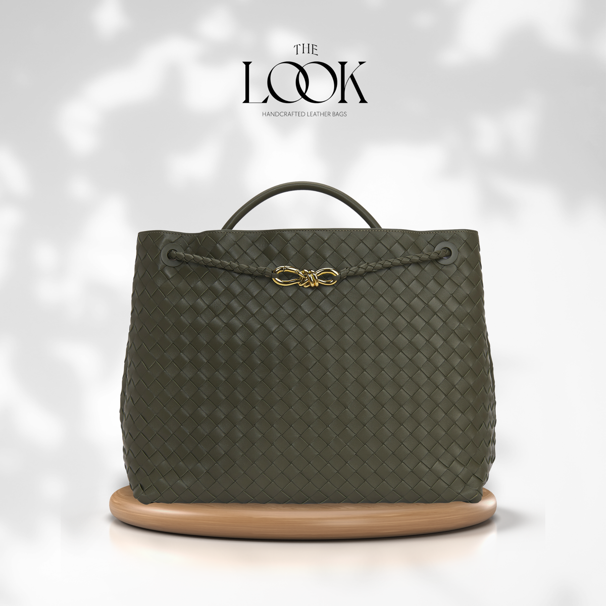 The Loop Jumbo Satchel in olive woven leather with gold hardware and top handle, front view.