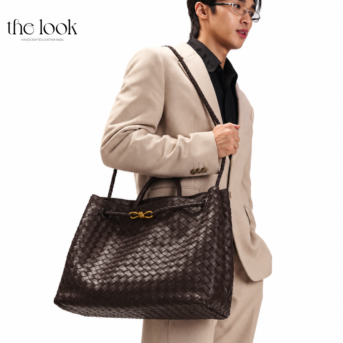 Model wearing The Loop Jumbo Satchel in Ebene woven leather with gold hardware over the shoulder.