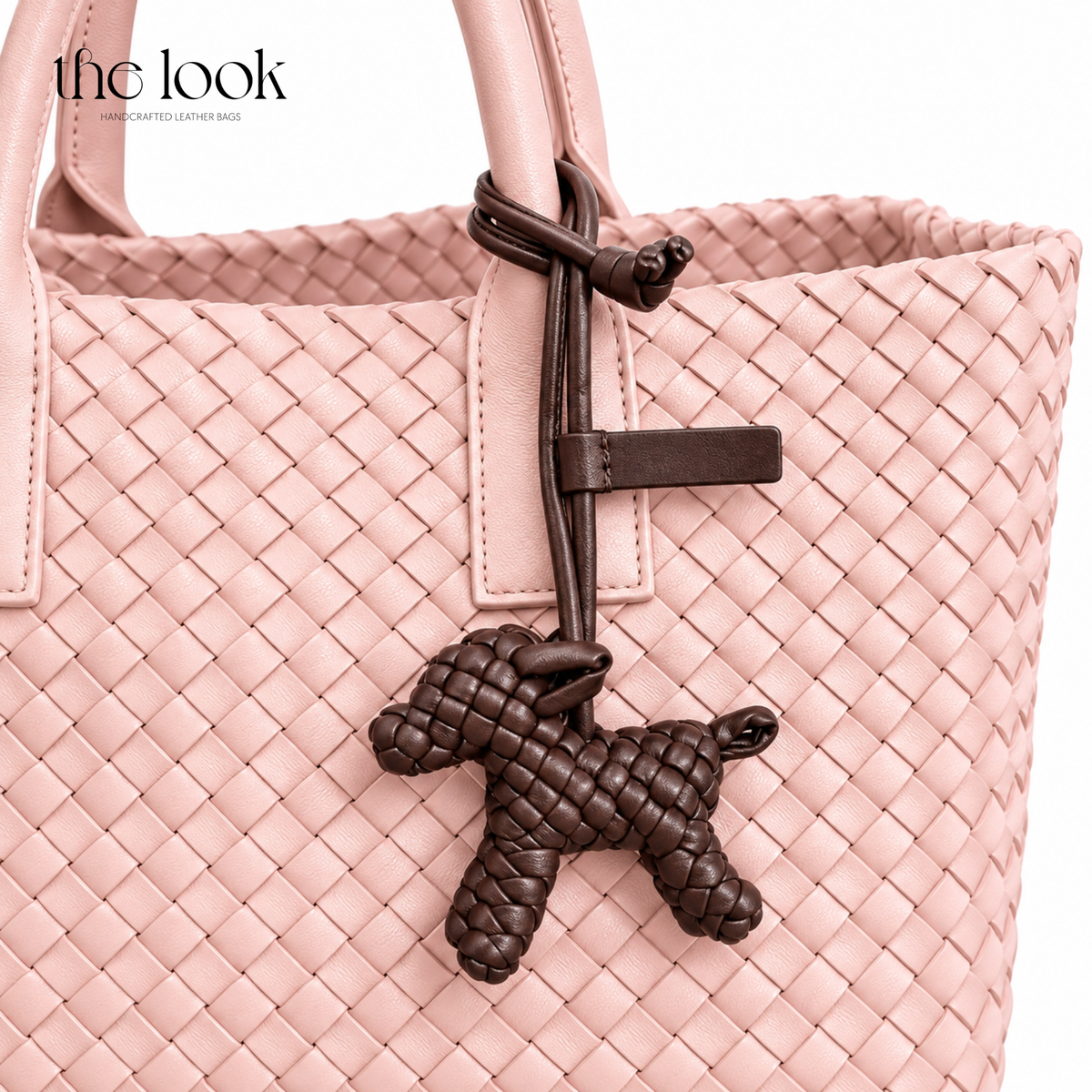 The Loop Pupper Bag Charm in Ebene Brown styled on a blush pink woven tote