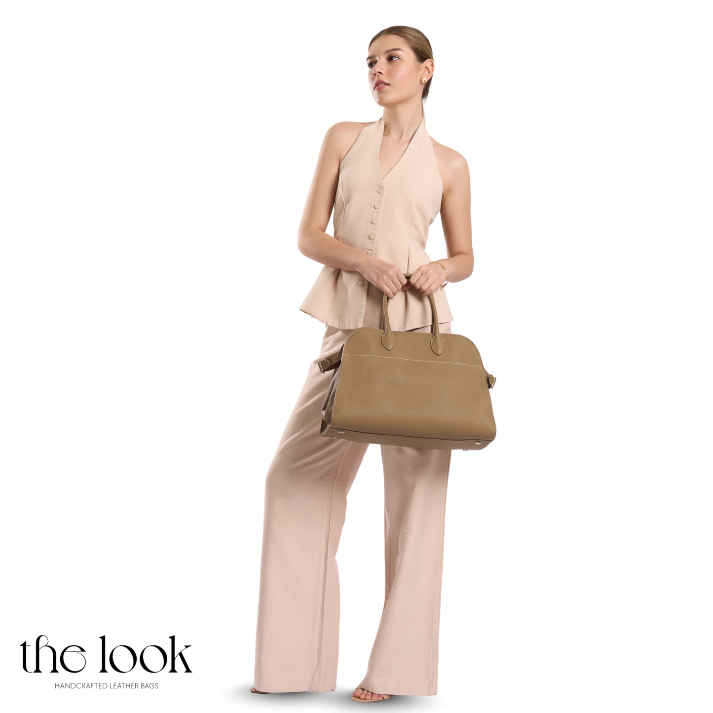 Woman holding a beige handbag wearing a matching outfit with 'the look' branding. | The Look Officiel