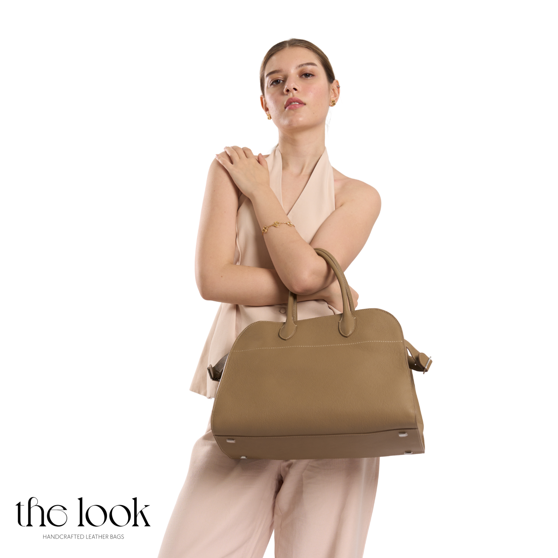Woman holding a brown handbag against a white background with 'the look' branding. | The Look Officiel