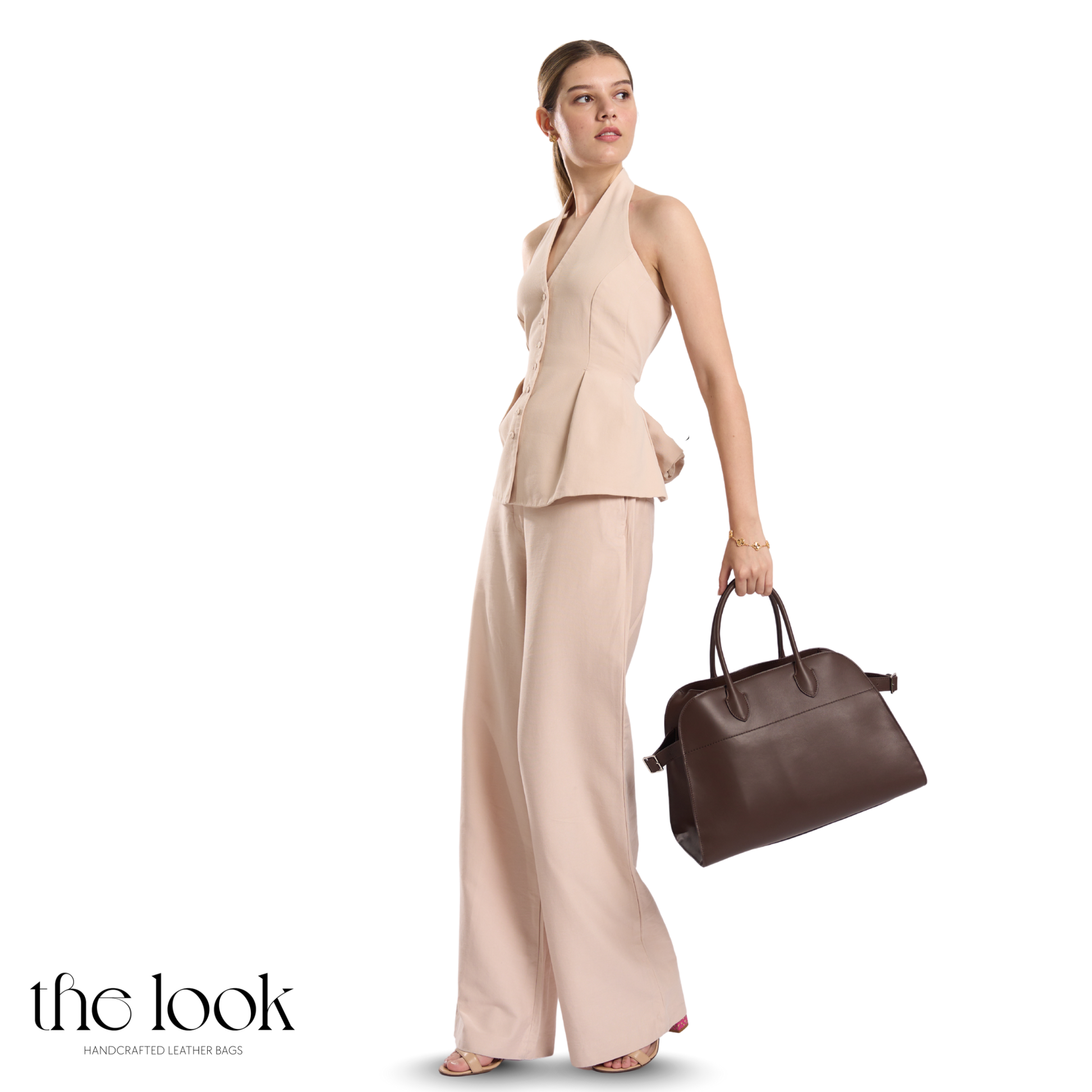 Woman in a beige outfit holding a brown leather bag on a white background | The Look Officiel