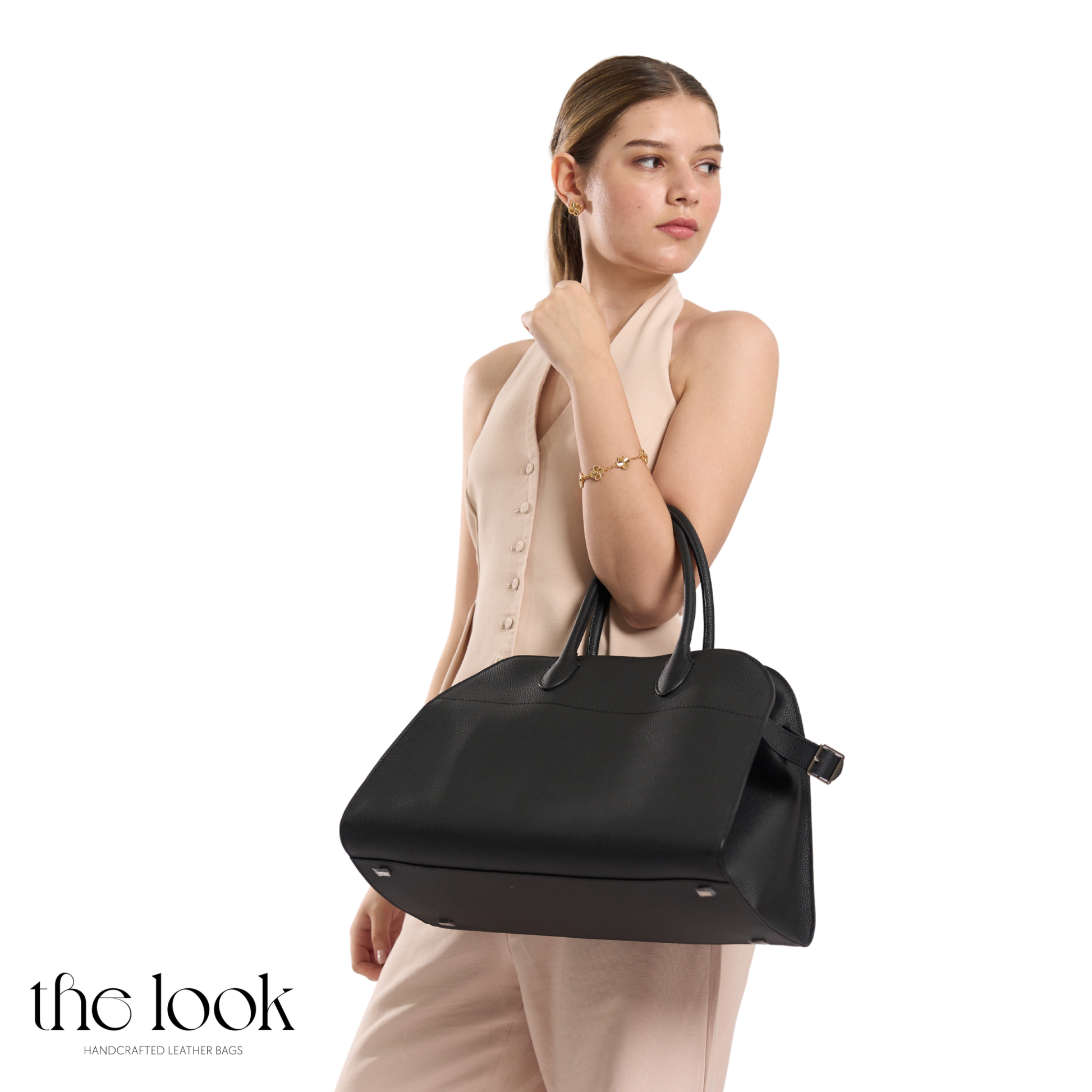 Woman holding a black handbag against a white background | The Look Officiel