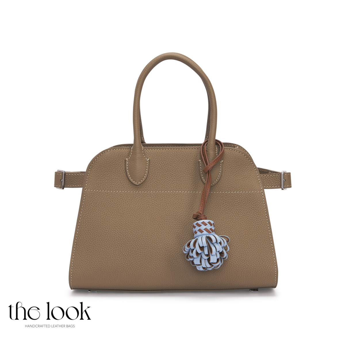 Pompette Cornflower Blue leather bag charm hanging from a taupe structured handbag, featuring layered blue and brown loops | The Look Officiel