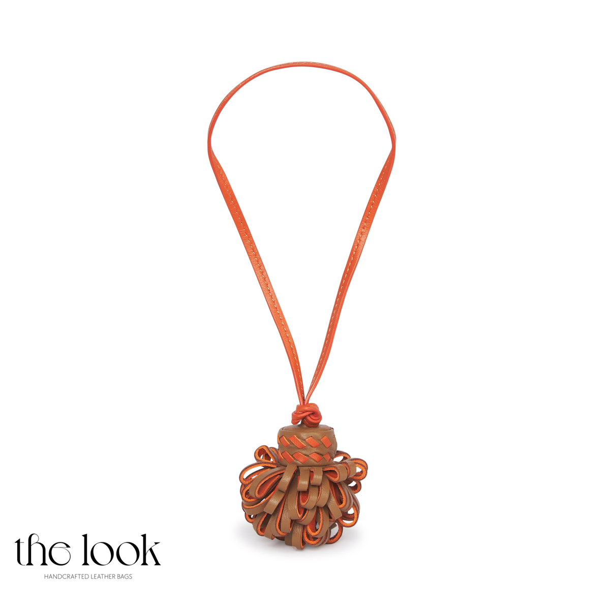 Pompette Gold Tan leather bag charm with orange accents, layered leather loops, and an orange hanging loop | The Look Officiel