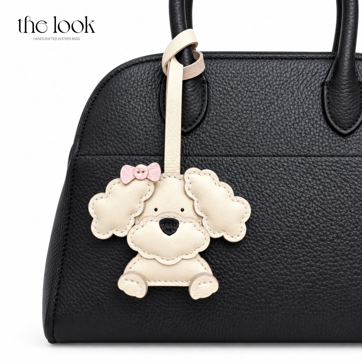Lulu the Cream Poodle dog bag charm styled on a black handbag | The Look Officiel