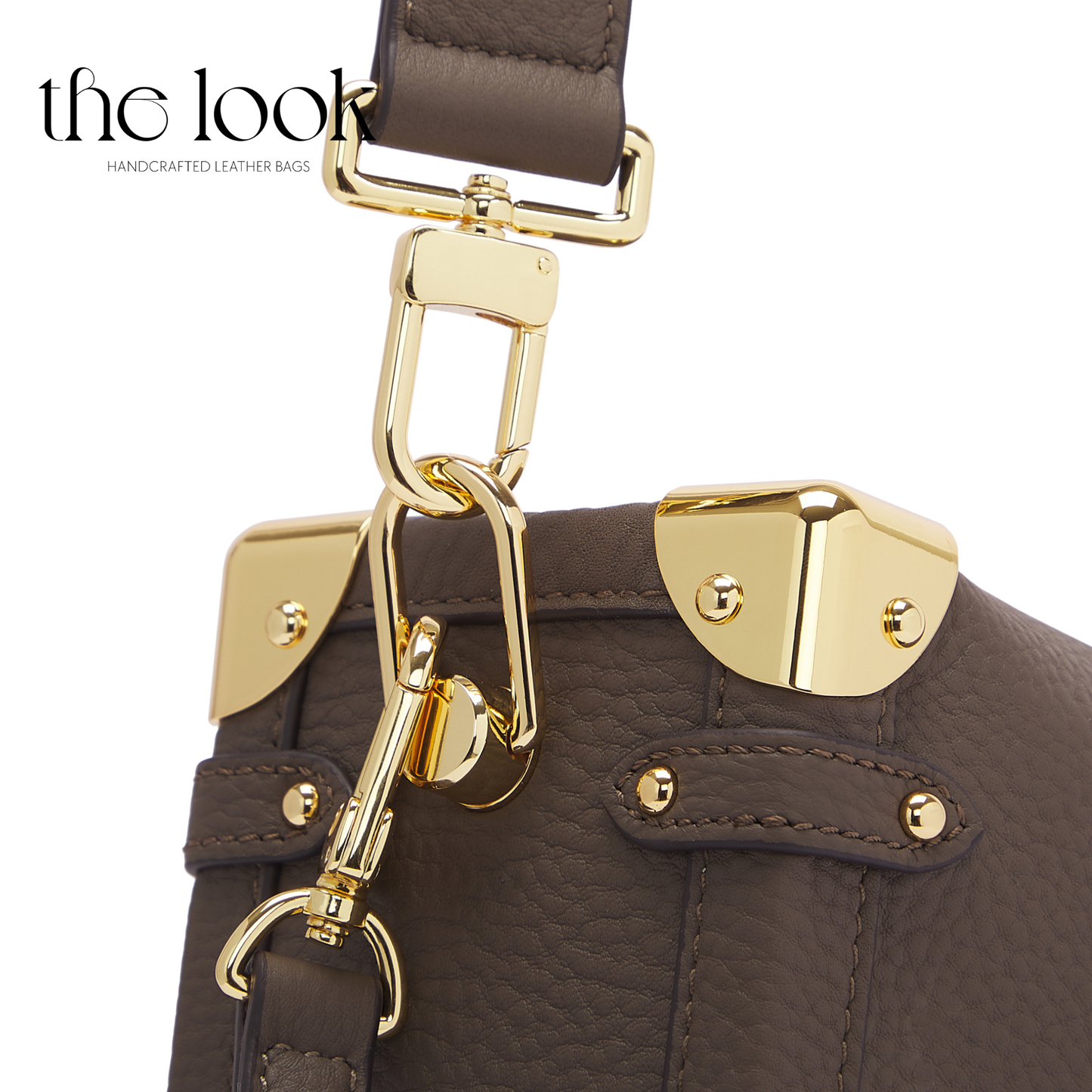 Brown leather handbag with gold hardware on a white background. | The Look Officiel