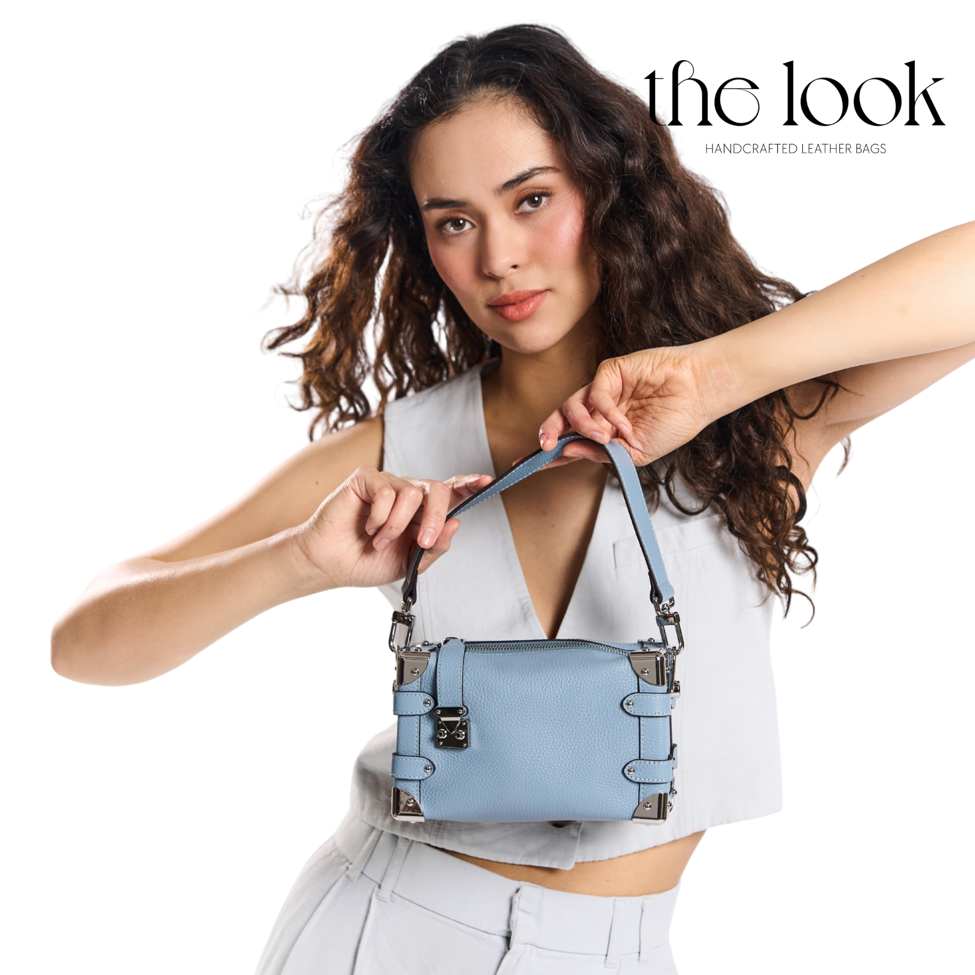 Woman holding a blue handbag with 'the look' branding. | The Look Officiel