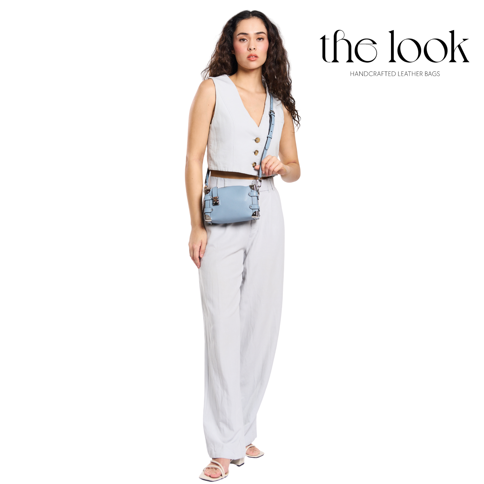 Woman holding a handbag with 'the look' brand on a white background. | The Look Officiel