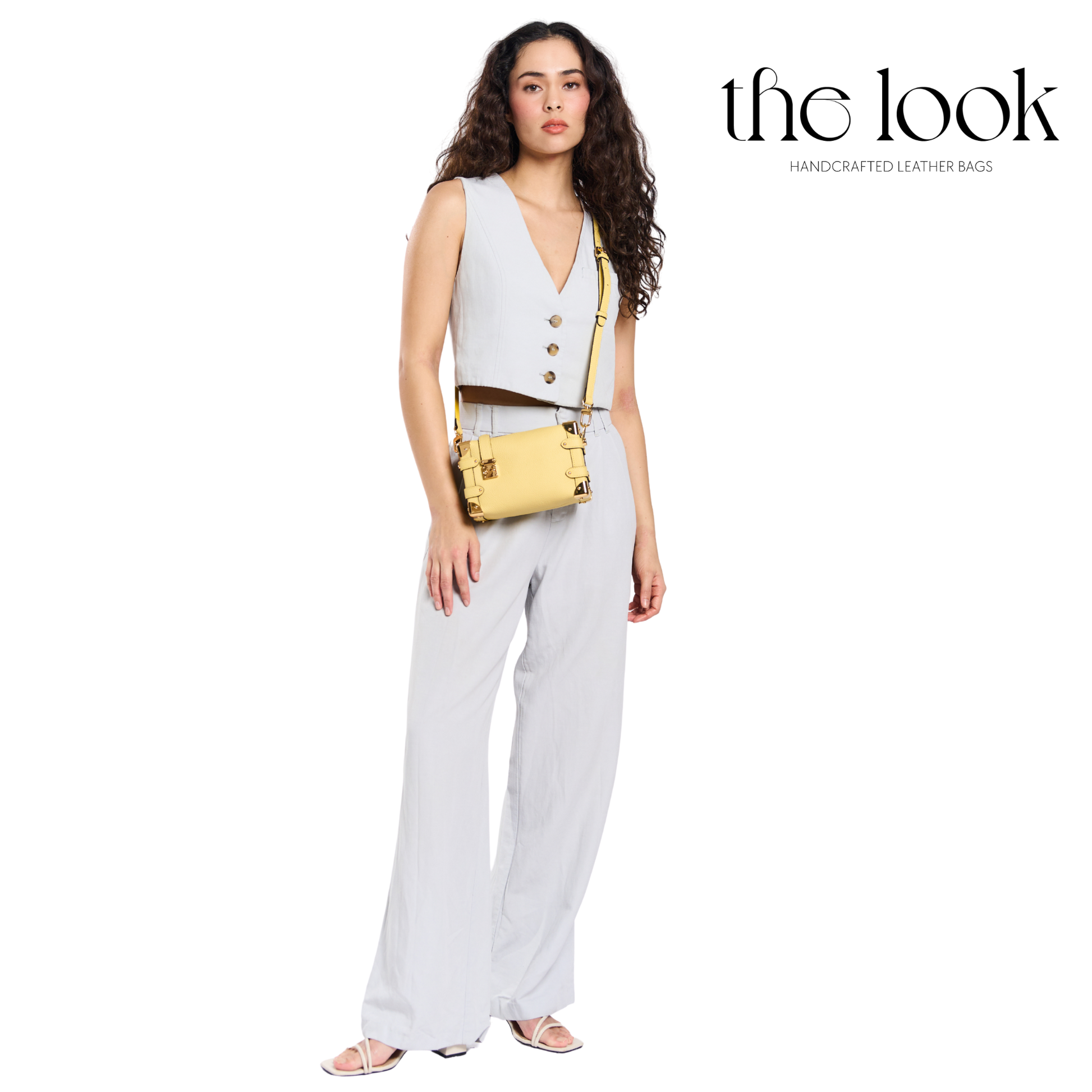 Woman wearing a light gray sleeveless top and pants with a gold handbag, branded 'the look'. | The Look Officiel