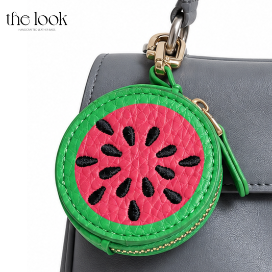 Open Watermelon Tutti Frutti Bag Charm attached to a gray leather handbag | The Look Officiel
