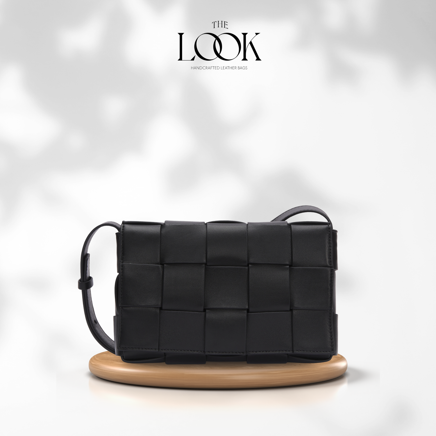 Black woven handbag on a wooden stand with 'The Look' branding. | The Look Officiel